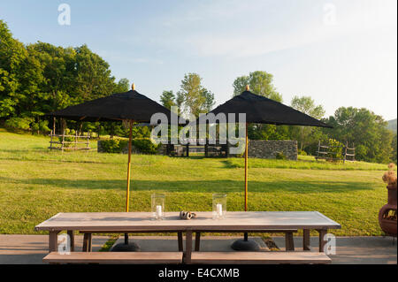Black parasols on terrace with table and bench and garden views