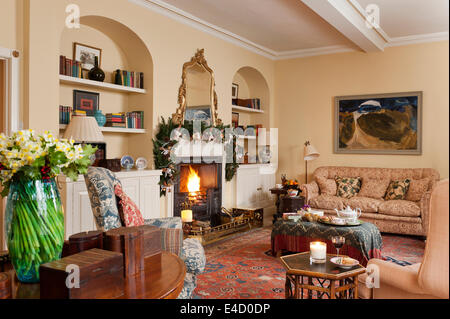 Cosy sitting room with fireplace and assorted antique furniture. The sofa is early 19th century and upholstered in Bennison line Stock Photo