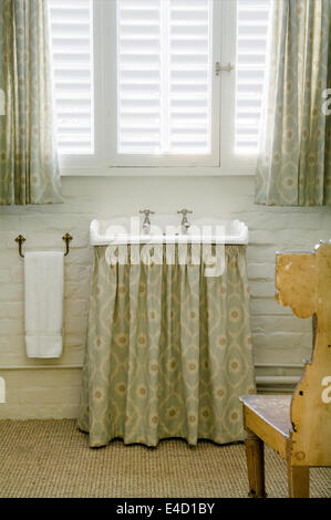 Freestanding wash basin with Soundness by Veere Greeney fabric used as curtain Stock Photo