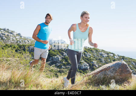 Fit couple jogging through countryside Stock Photo