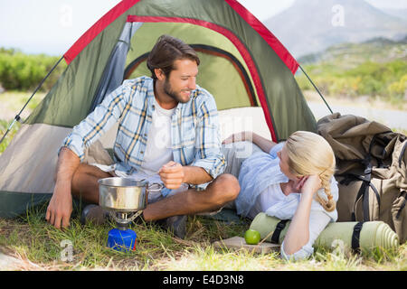 Attractive happy couple cooking on camping stove Stock Photo