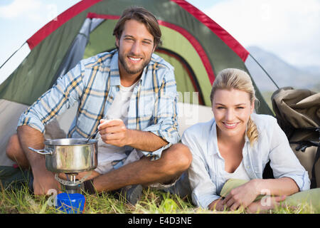 Attractive happy couple cooking on camping stove Stock Photo