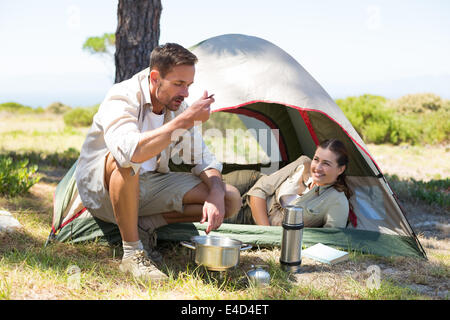 Outdoorsy couple cooking on camping stove outside tent Stock Photo