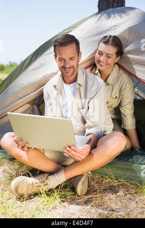 Outdoorsy couple looking at the laptop outside tent Stock Photo