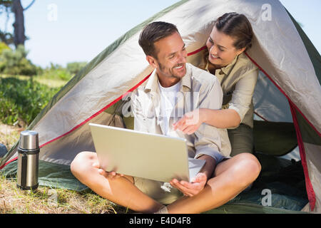 Outdoorsy couple looking at the laptop outside tent Stock Photo