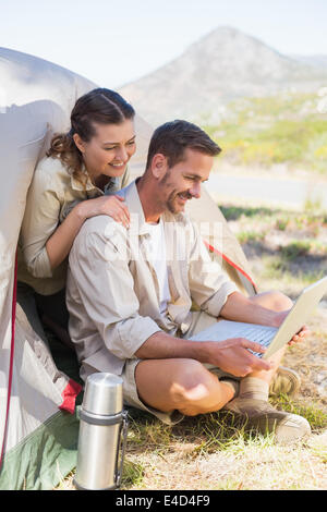 Outdoorsy couple looking at the laptop outside tent Stock Photo