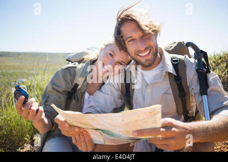 Hiking couple taking a break on mountain terrain using map and compass Stock Photo