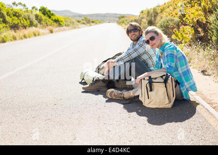 Attractive couple sitting on the road waiting for a lift Stock Photo