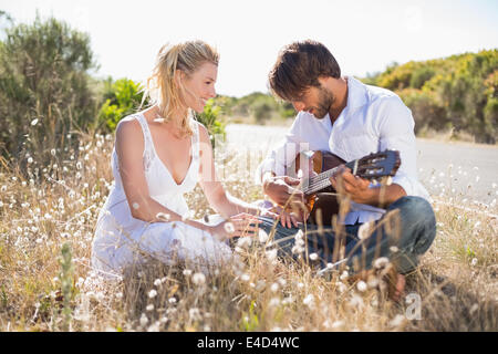 Handsome man serenading his girlfriend with guitar Stock Photo