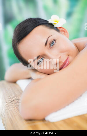 Beautiful brunette relaxing on massage table smiling at camera Stock