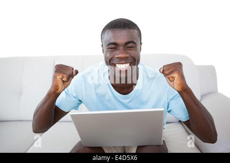 Cheering man sitting on couch using laptop Stock Photo