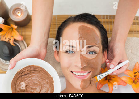 Peaceful brunette getting a mud facial applied Stock Photo