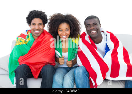 Happy football fans wrapped in flags smiling at camera Stock Photo