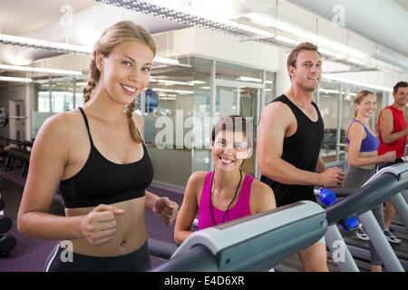 Trainer and clients smiling at camera on the treadmill Stock Photo