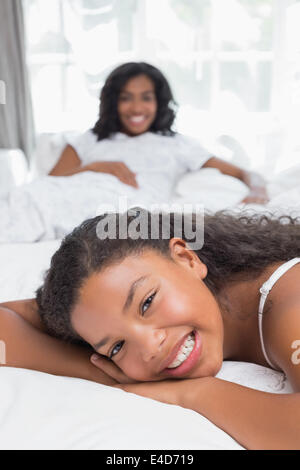 Happy mother and daughter relaxing on bed together Stock Photo