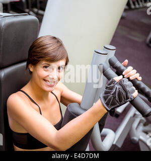 Focused brunette using weights machine for arms Stock Photo