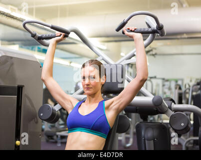 Fit focused brunette using weights machine for arms Stock Photo