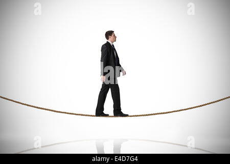 Composite image of handsome businessman stepping on tightrope Stock Photo