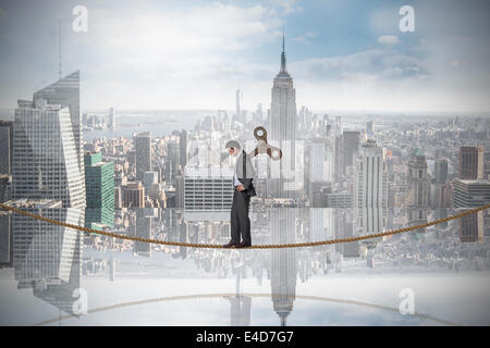 Composite image of wound up businessman with hands on hips on tightrope Stock Photo