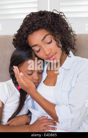 Pretty mother sitting on the couch with her sleeping daughter Stock Photo