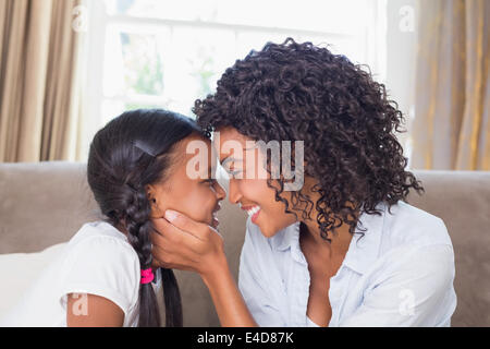 Pretty mother sitting on couch with cute daughter Stock Photo