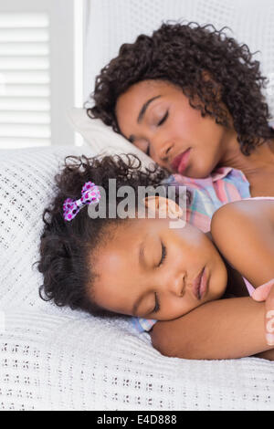 Cute daughter sleeping with mother on the sofa Stock Photo