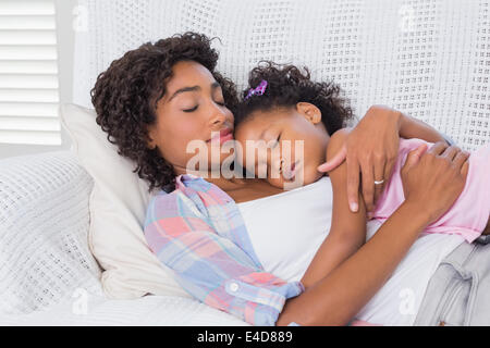 Cute daughter sleeping with mother on the sofa Stock Photo