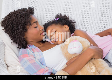 Cute daughter sleeping with mother on the sofa Stock Photo