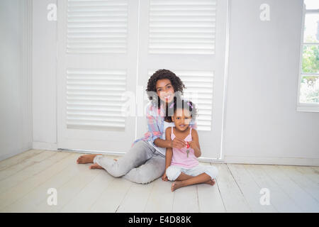 Mother and daughter sitting on the floor showing new house key Stock Photo