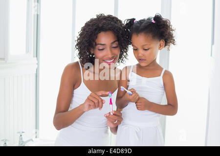 Pretty mother showing her daughter her toothbrush Stock Photo