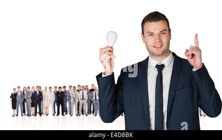 Composite image of businessman holding light bulb and pointing Stock Photo