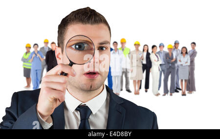 Composite image of businessman looking through magnifying glass Stock Photo