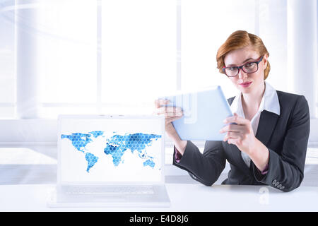 Composite image of redhead businesswoman using her tablet pc Stock Photo