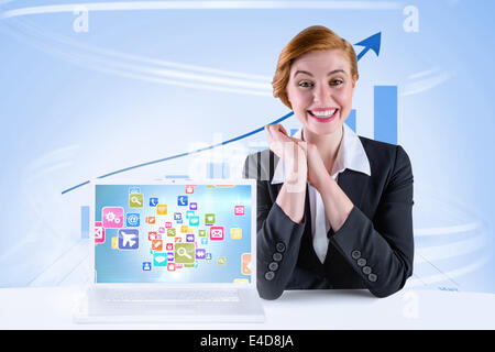 Composite image of excited redhead businesswoman sitting at desk Stock Photo