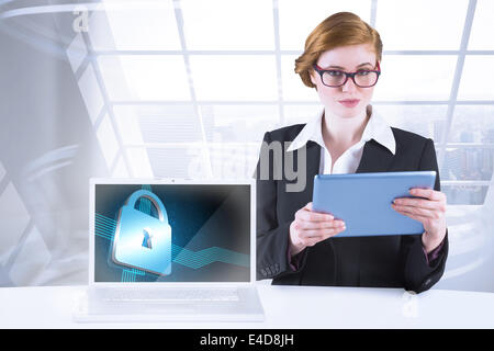 Composite image of redhead businesswoman using her tablet pc Stock Photo