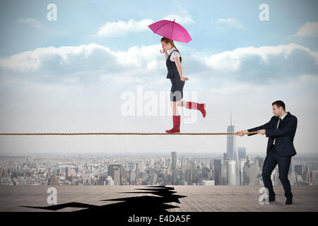Young business man pulling a tightrope for businesswoman Stock Photo
