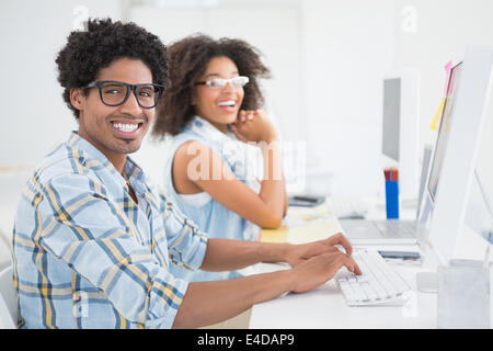 Happy design team smiling at camera working at desk Stock Photo