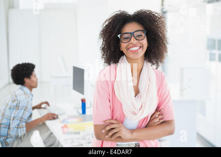 Young designer smiling at camera with colleague behind her Stock Photo