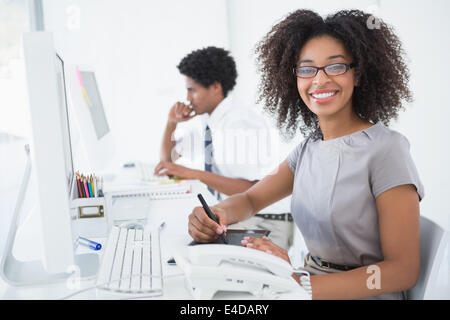 Young pretty designer smiling at camera at her desk Stock Photo