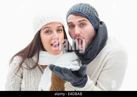 Attractive young couple in warm clothes blowing Stock Photo