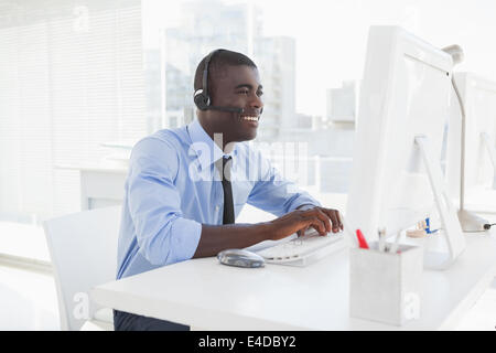 Happy businessman working at his desk wearing headset Stock Photo