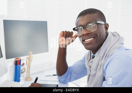 Hipster businessman smiling at camera at his desk Stock Photo