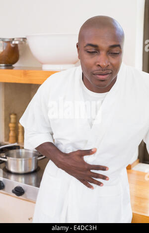 Sick man in bathrobe clutching stomach Stock Photo