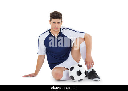 Football player sitting on the ground with ball Stock Photo