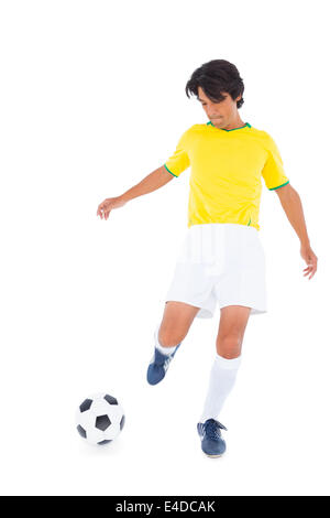 Football player in yellow kicking ball Stock Photo