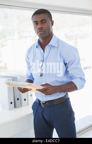 Serious businessman holding documents looking at camera Stock Photo