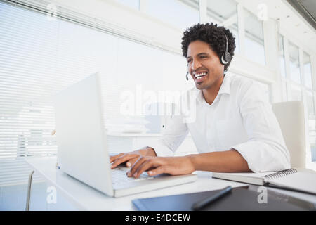 Happy businessman working at his desk wearing headset Stock Photo