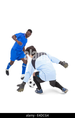 Football player in blue striking at keeper Stock Photo