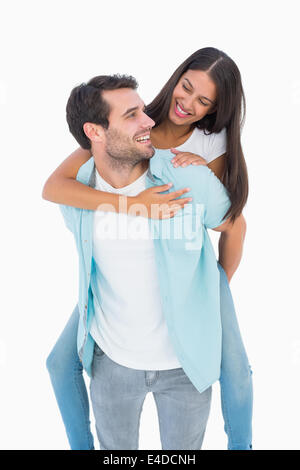 Happy casual man giving pretty girlfriend piggy back Stock Photo