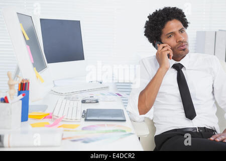 Serious businessman working at his desk on the phone Stock Photo